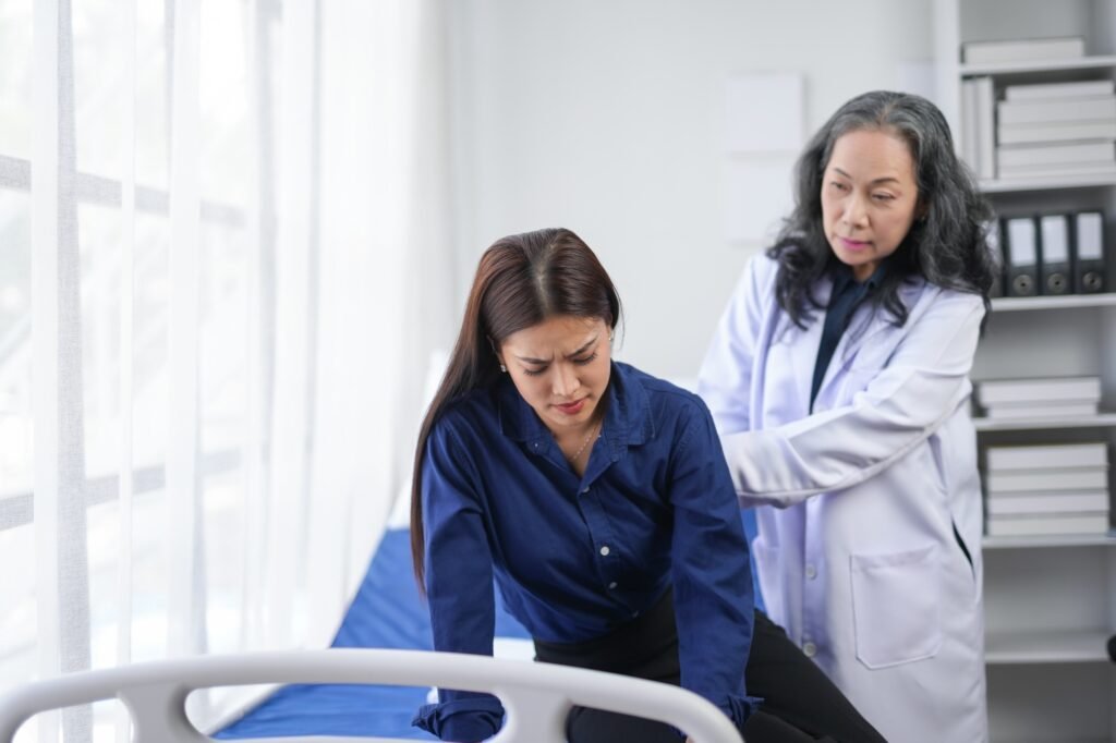 A female doctor assists a woman experiencing back pain in a medical office